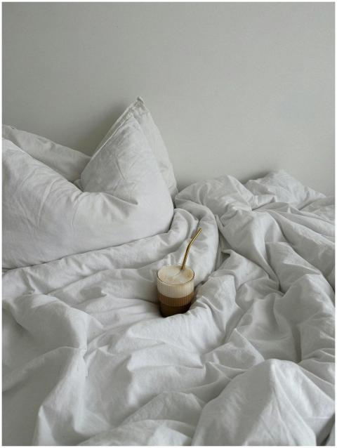 A cozy bedroom with a glass of coffee resting on w