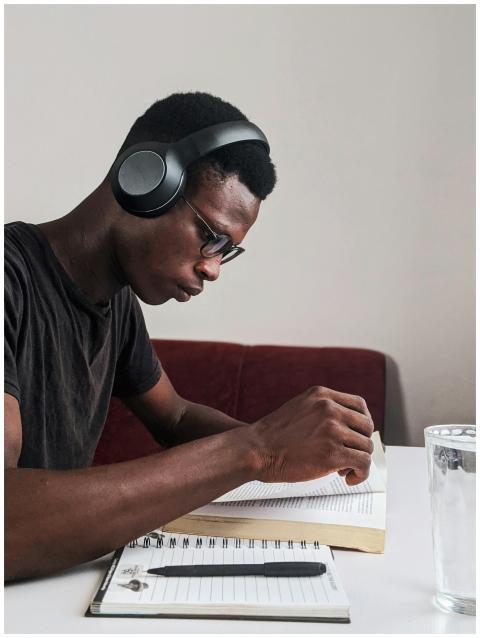 An adult man intensely studying with headphones, p