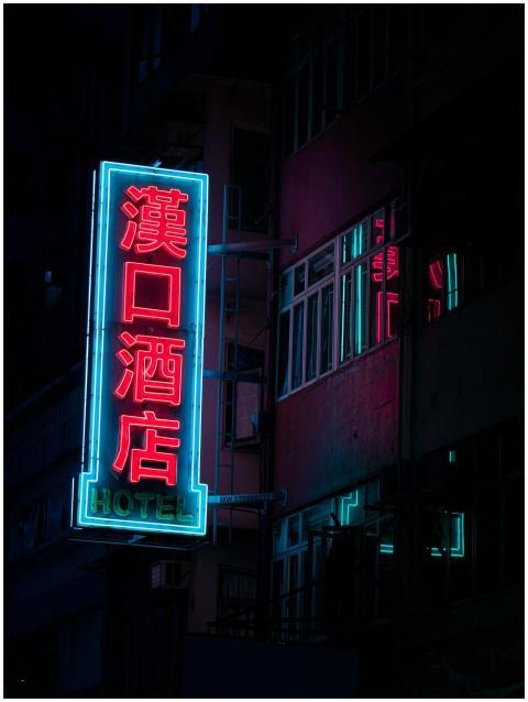 Vibrant neon hotel sign glowing on a dark Hong Kon