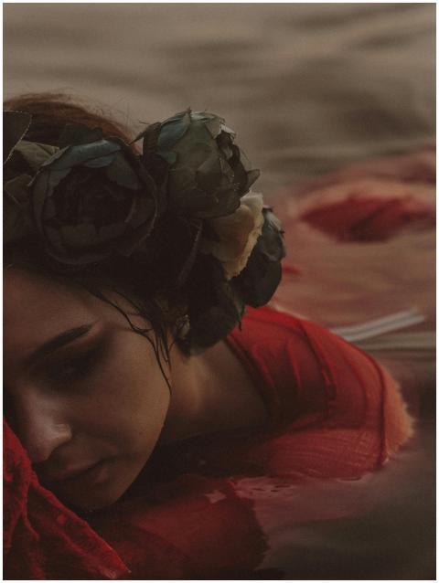 A woman in a red dress is submerged in water, wear