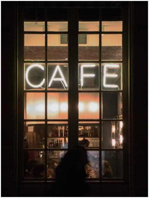 Night view of a bustling Paris café through a wind