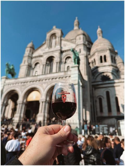 A person holding a glass of red wine in front of S