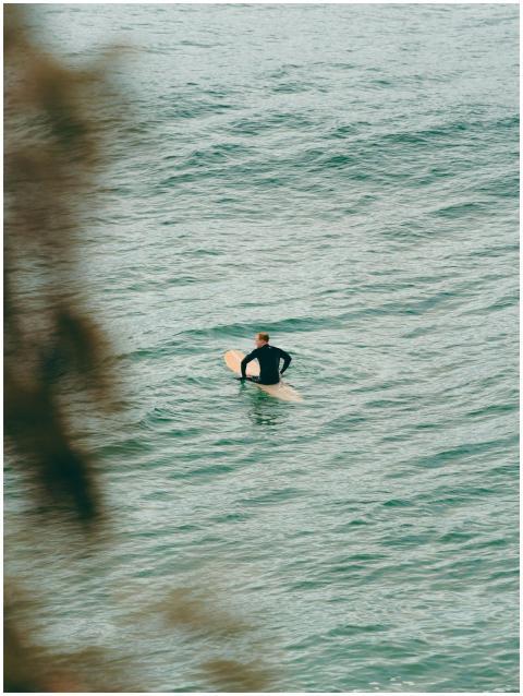 A lone surfer paddles on calm ocean waters in Byro