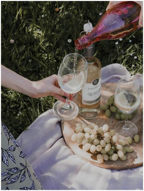 A refreshing outdoor picnic scene with wine pourin
