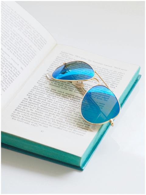 Blue sunglasses rest on an open book, highlighting