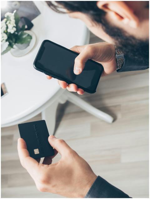 A man using a smartphone and credit card for an on