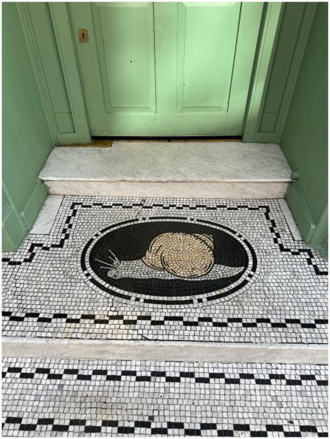 Detailed snail mosaic art at a residential entranc