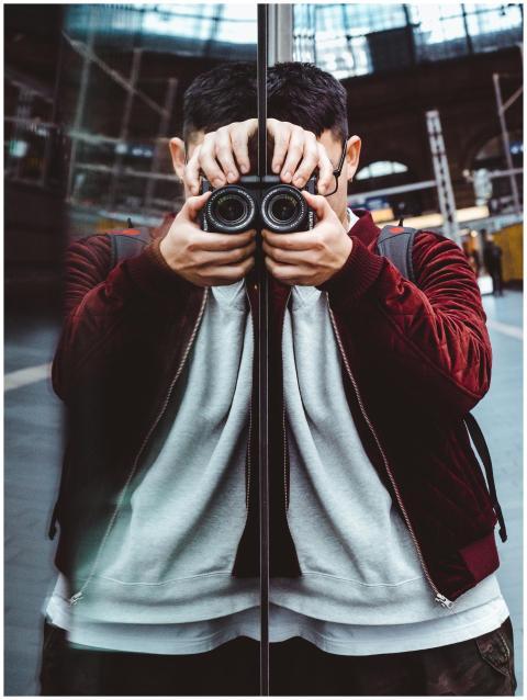 A photographer in a red jacket captures a reflecti