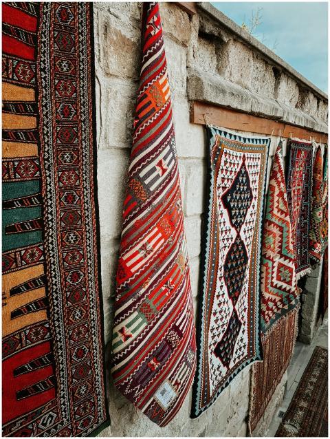Colorful handwoven rugs displayed on a stone wall