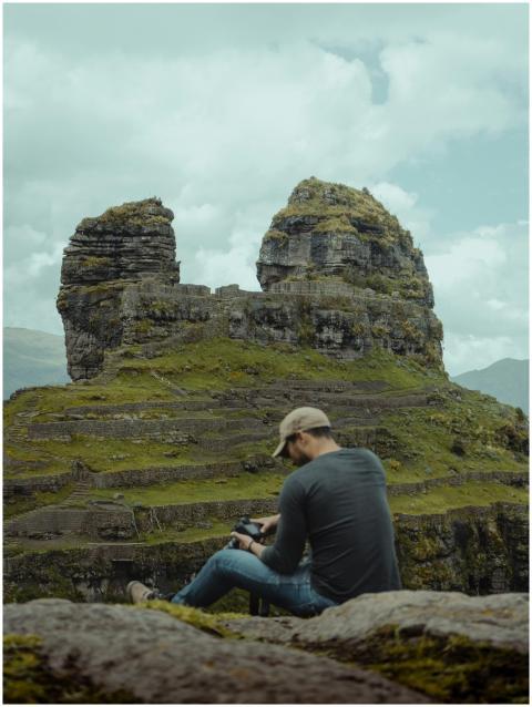 A man sitting in nature at a rock formation in Cus