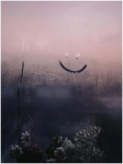 A hand-drawn smiley face on a fogged window with a