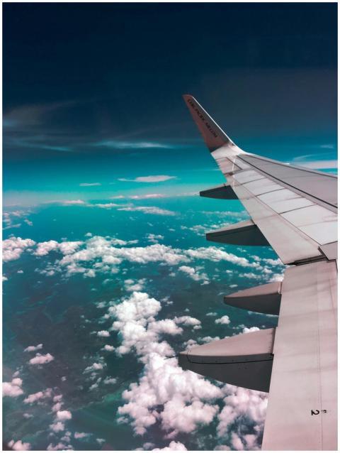 Aerial view of airplane wing over fluffy clouds wi