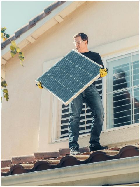 A technician is installing a solar panel on a hous