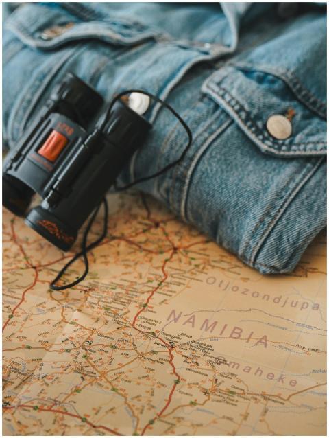 Binoculars and denim jacket on map of Namibia refl