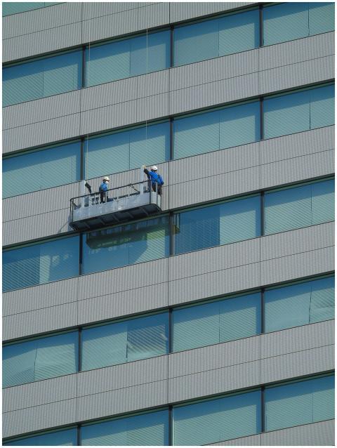 Two workers clean windows on a modern glass buildi