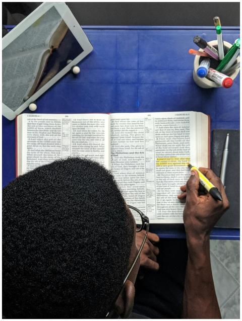 Man highlighting text while studying with a book a