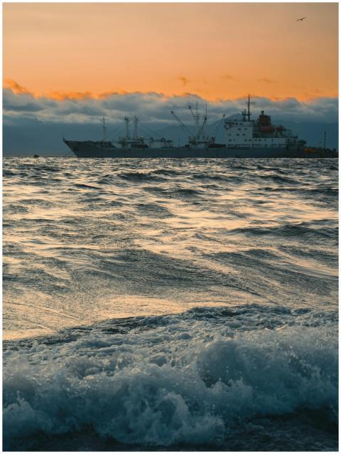 Peaceful sunset over ocean with a cargo ship in th