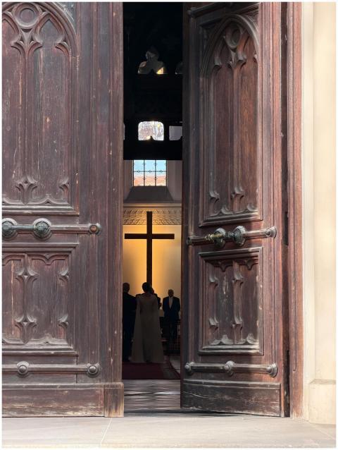 Gothic church door partially open, revealing a wed