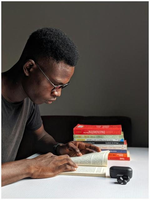 Young man studying intently with books in library