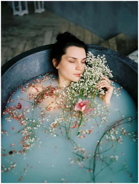 Woman relaxing in a bathtub filled with flowers an