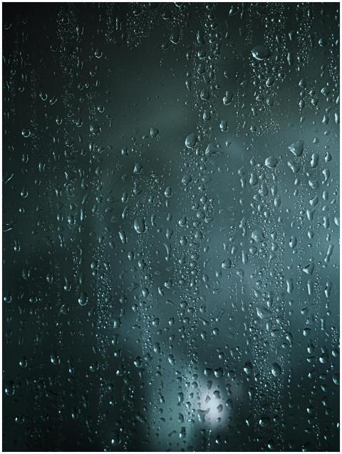 Rain droplets on a glass window create a textured,