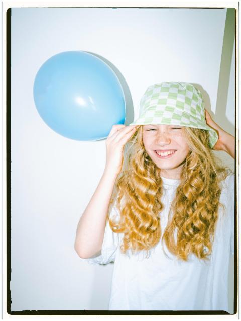 A cheerful young girl in a summer hat posing with