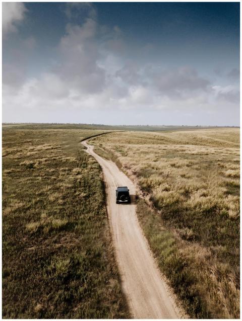 A vehicle travels on a winding dirt road through r