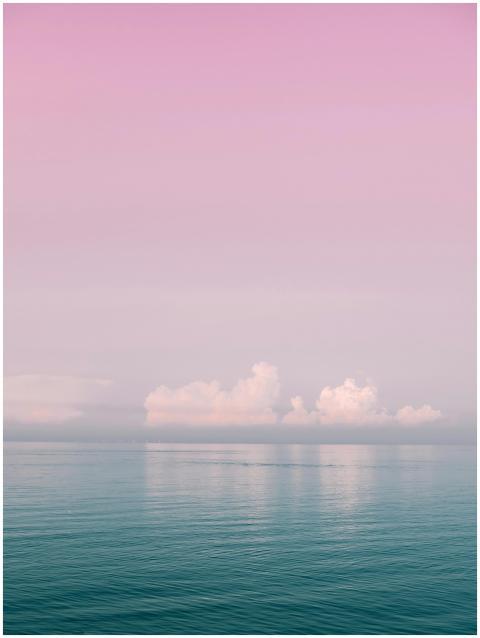 Serene ocean view with pink sky and soft clouds at