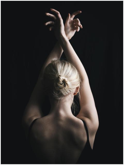 Elegant portrait of a woman with arms raised, high