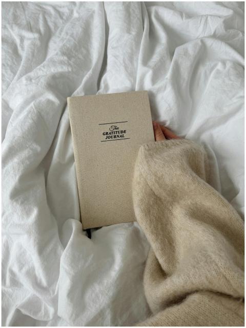 A close-up of a hand holding a gratitude journal o