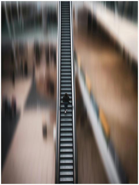 Blurred top view of a lone woman on an escalator,