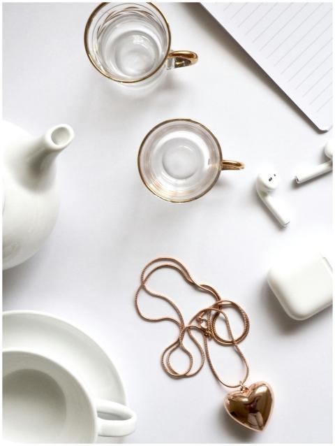 Minimalist flat lay featuring gold jewelry, glass