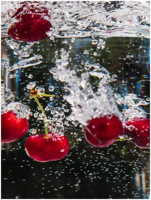 Vibrant red cherries plunge into sparkling water,