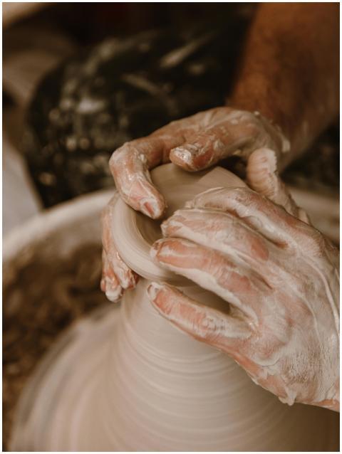 Artisan hands skillfully shaping wet clay on a pot