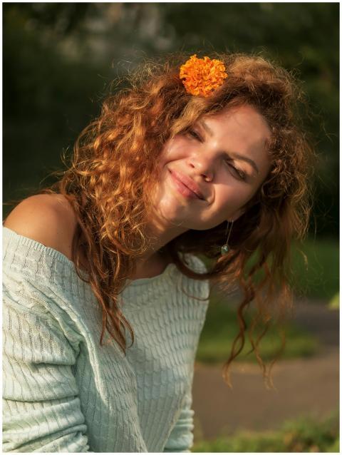 A young woman with curly hair and a flower accesso