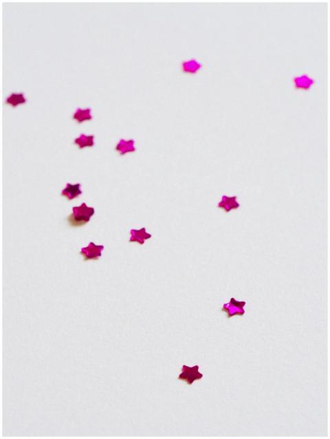 Bright pink star-shaped confetti scattered on a wh