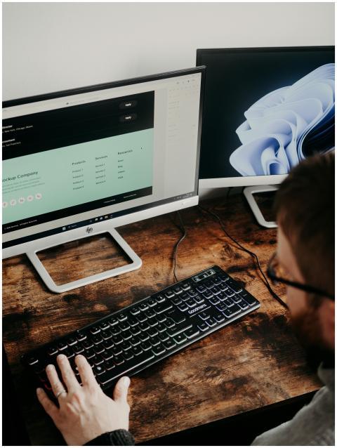 Adult man uses dual monitors for web design in a h