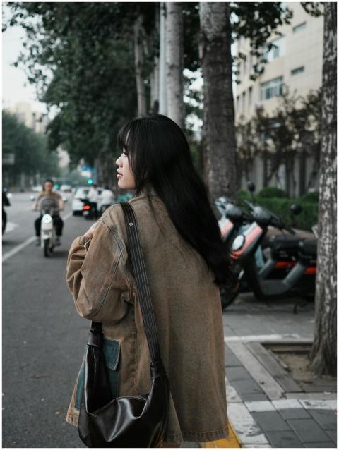 A young woman walks along a tree-lined city street