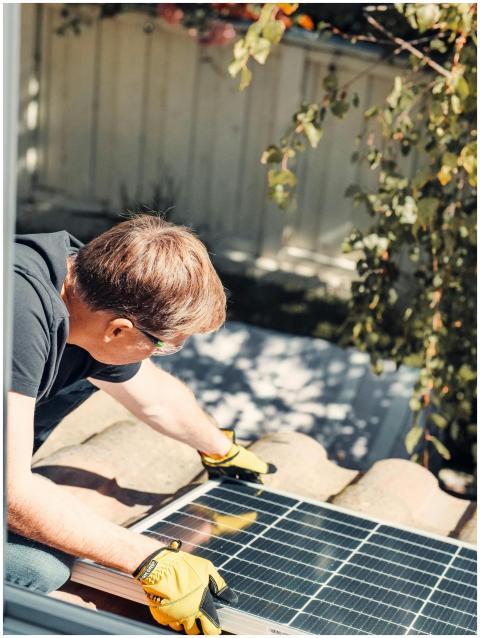 An adult male installing a solar panel on a roofto