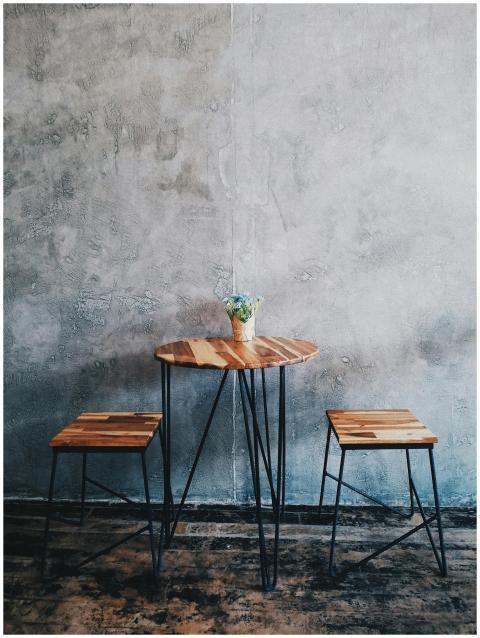 A minimalist wooden table with stools and a concre