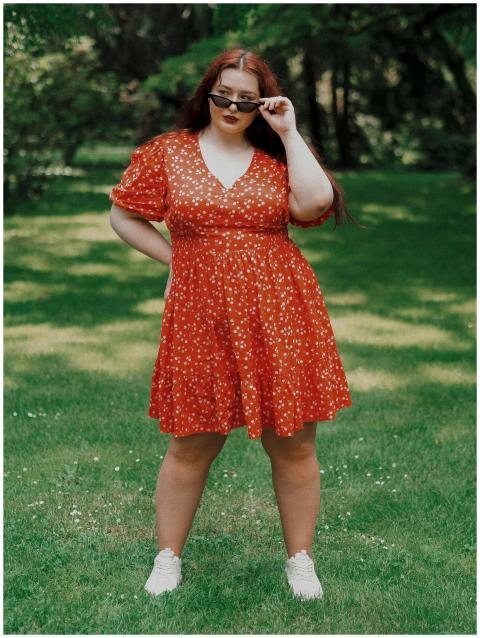 Confident woman posing outdoors in a red floral dr