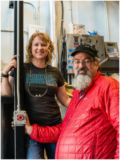 Two smiling workers in a brewing factory showcasin