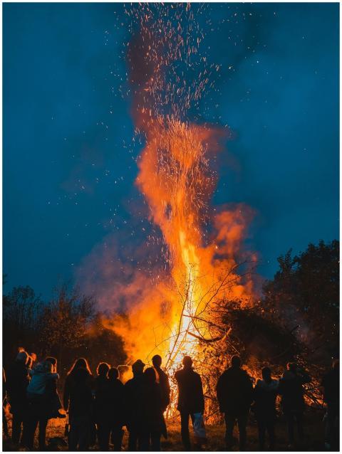 A group of people stands around a large bonfire un