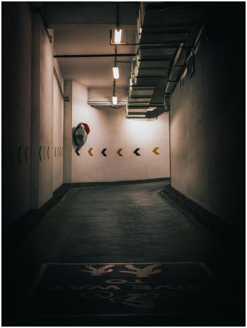 Dimly lit underground parking garage with directio