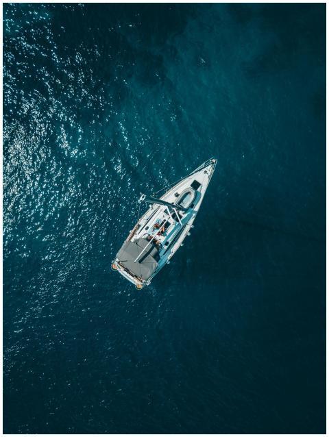 A stunning aerial shot of a sailboat cruising the