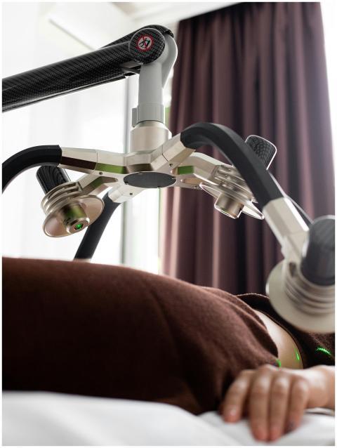 Crop anonymous female client lying under lasers of