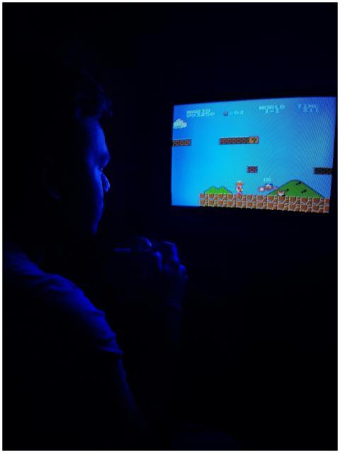 Man playing Super Mario Bros on TV, capturing retr
