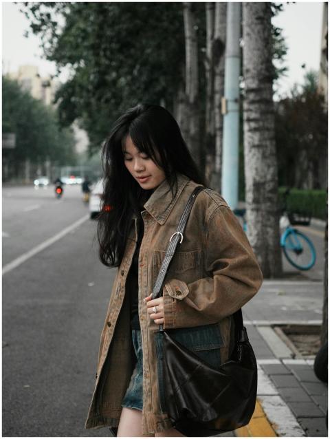 A stylish young woman walks along a tree-lined cit