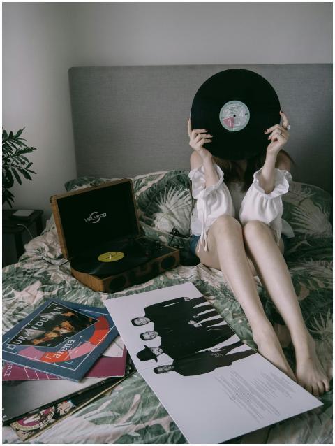 Woman holding a vinyl record on a bed with a recor