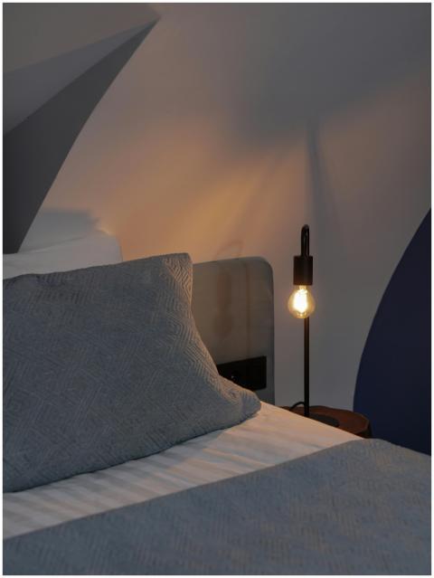A serene bedroom with a glowing bulb lamp casting